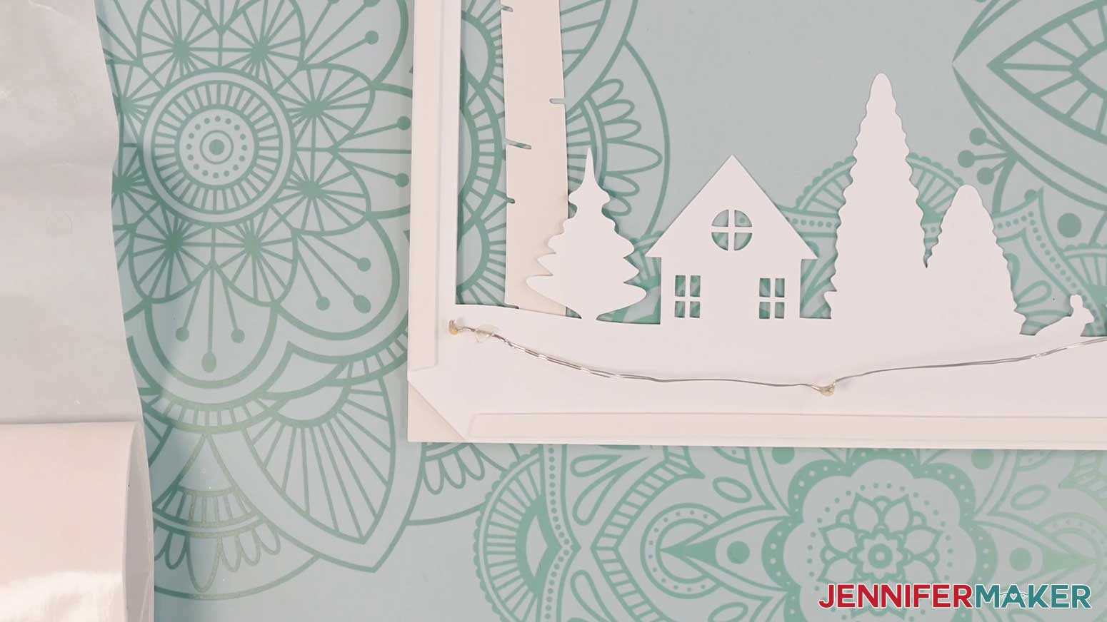 Secure the end of the light strip with a glue dot to begin adding lights to the Village Shadow Box With Lights.