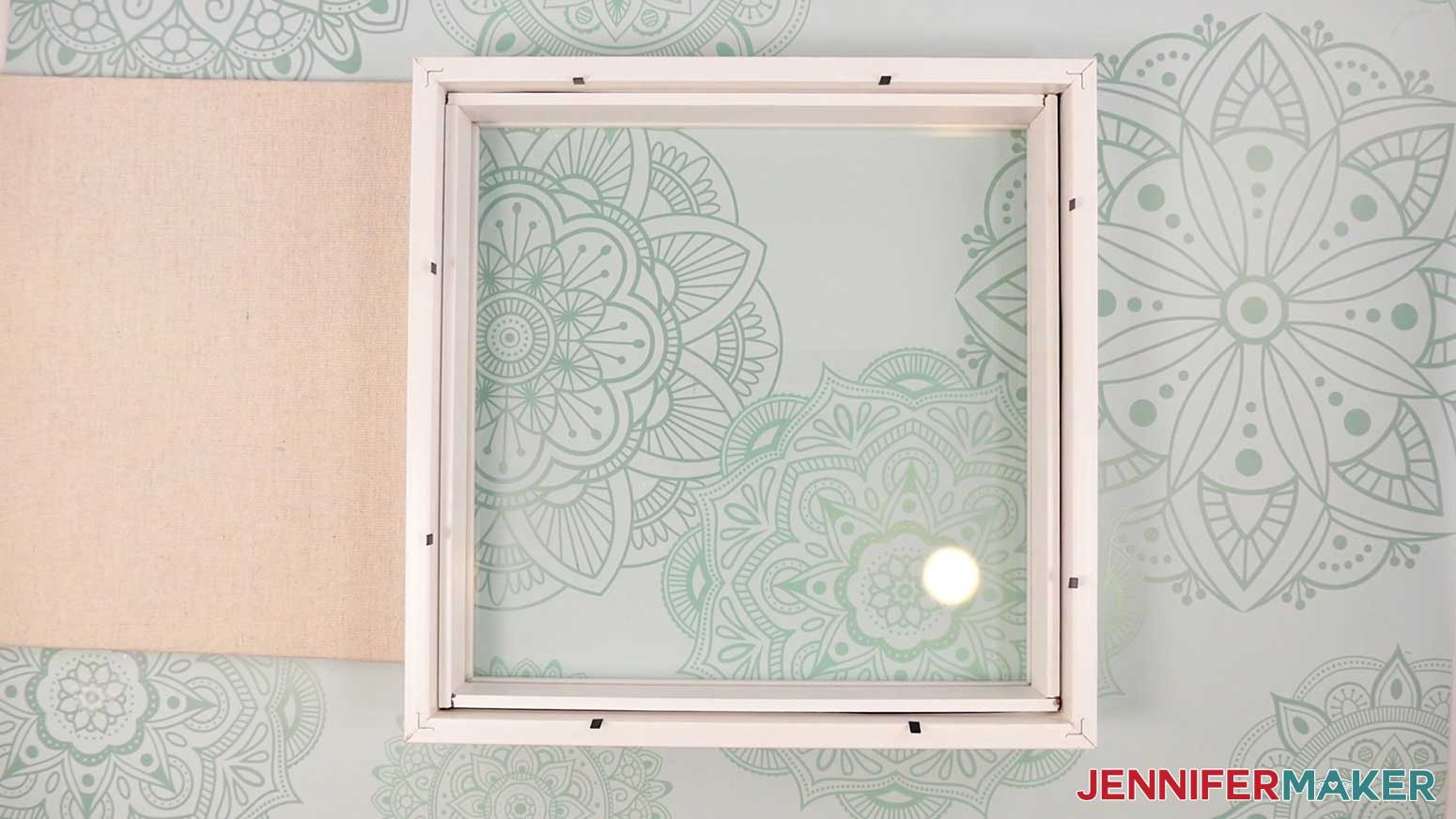 Remove the backer of the frame for the Village Shadow Box With Lights.