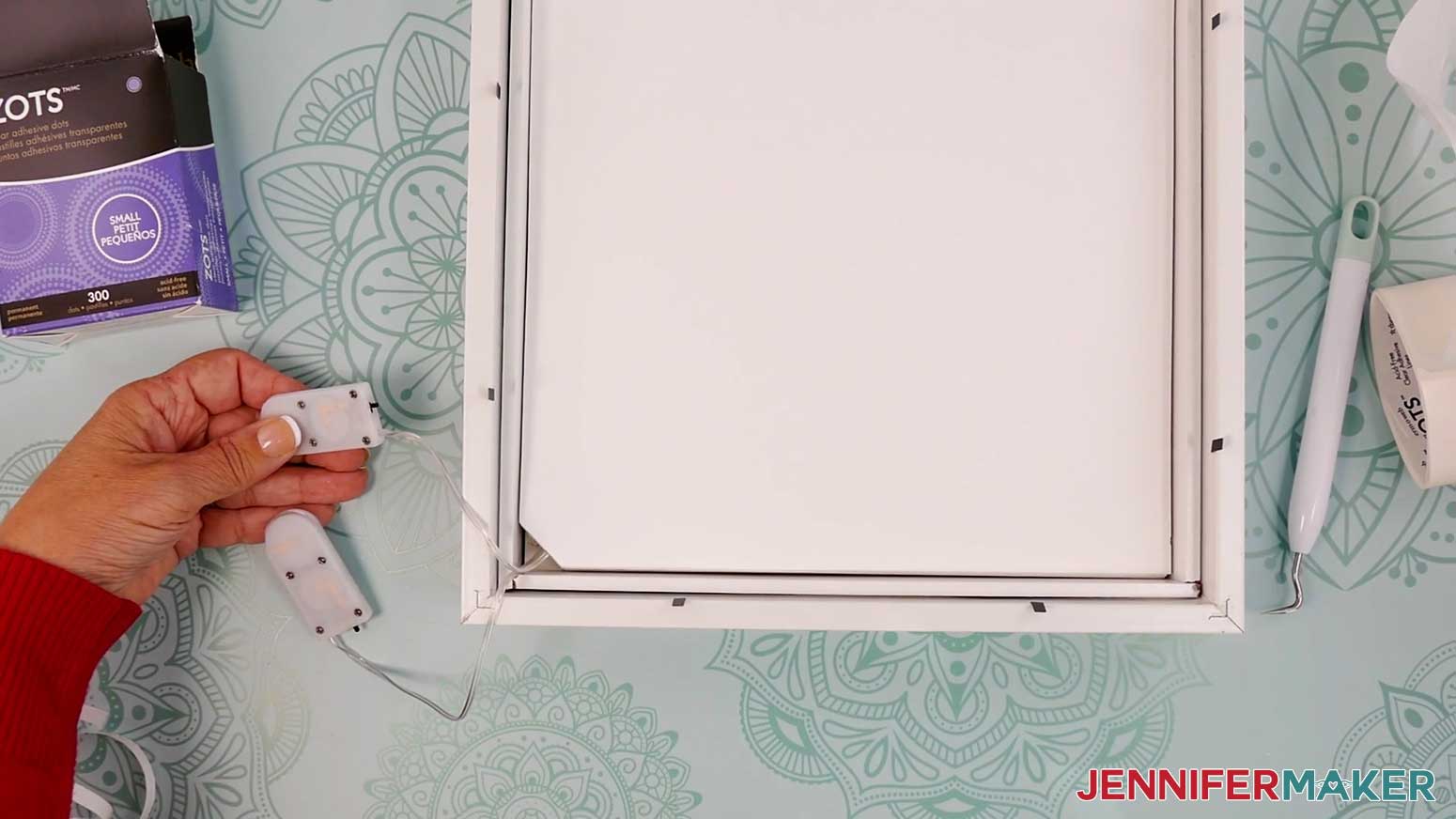 Feed the wires of the Village Shadow Box With Lights out through the bottom notched corner of Layer 7.