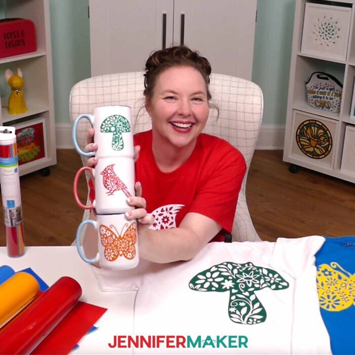Jennifer Maker shows off a stack of mugs decorated with different colored floral wildlife vinyl decals. Learn how to use Adhesive Vinyl Vs Iron-On For Cricut Beginners