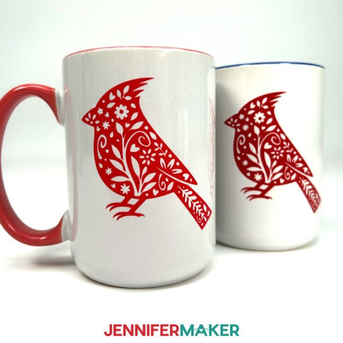 Two white mugs with red adhesive vinyl cardinal designs. Learn how to use Adhesive Vinyl Vs Iron-On For Cricut Beginners