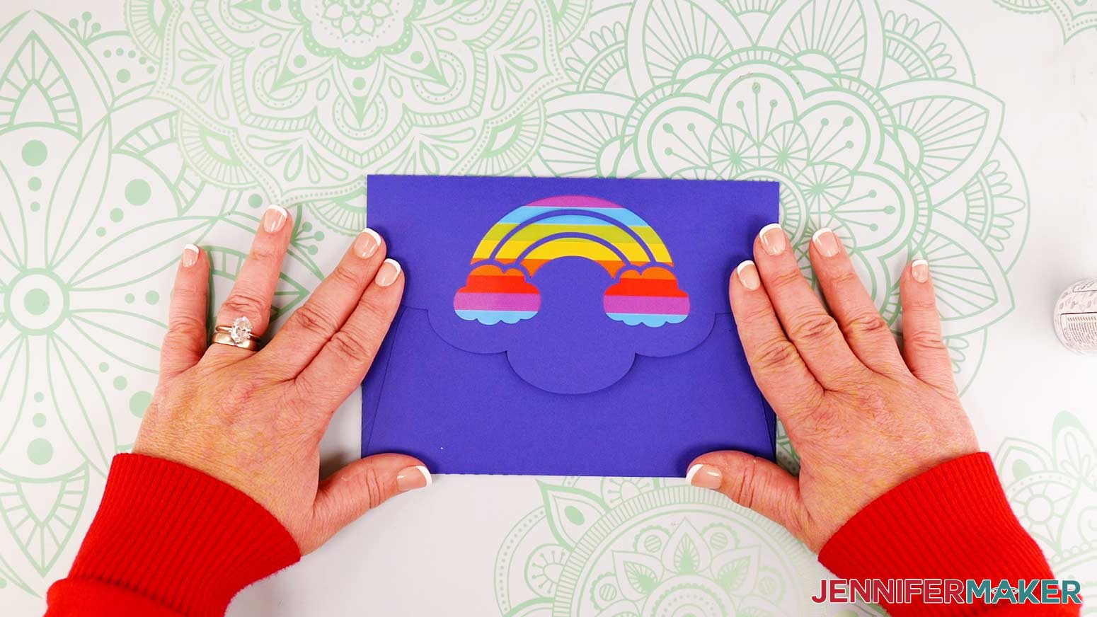 The assembled waterfall card envelope with the flap closed, showing the rainbow liner through the rainbow design cutout.