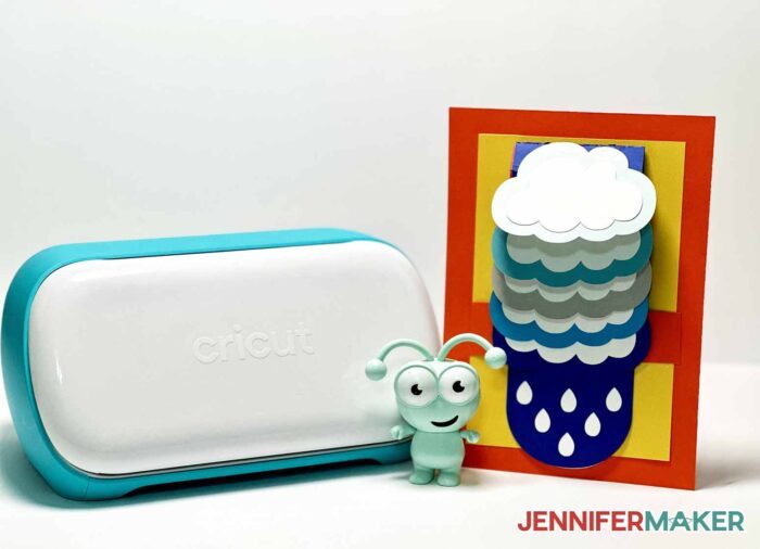 A waterfall card resized to cut on a Cricut Joy next to the machine and a green Cricut Cutie.