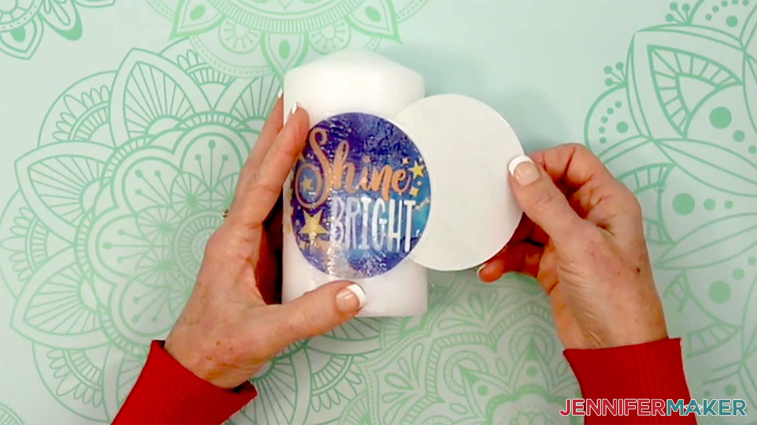 The left hand holds the decal while the right had slides the paper backer from beneath the decal.