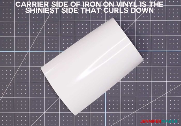 A piece of white iron-on vinyl showing the shiny carrier side which is the side you put down on your cutting mat