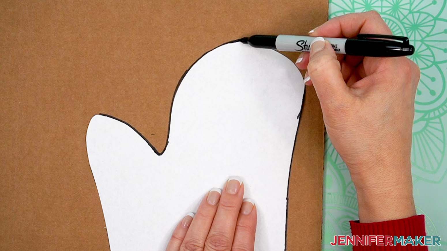 Use a marker to trace the shape of the oven mitt insert onto a piece of cardboard.