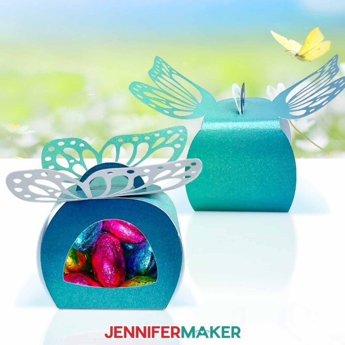 Two Window Treat Boxes, both blue ombre with a butterfly cutout on top, show wrapped multicolored chocolate eggs through the acetate window