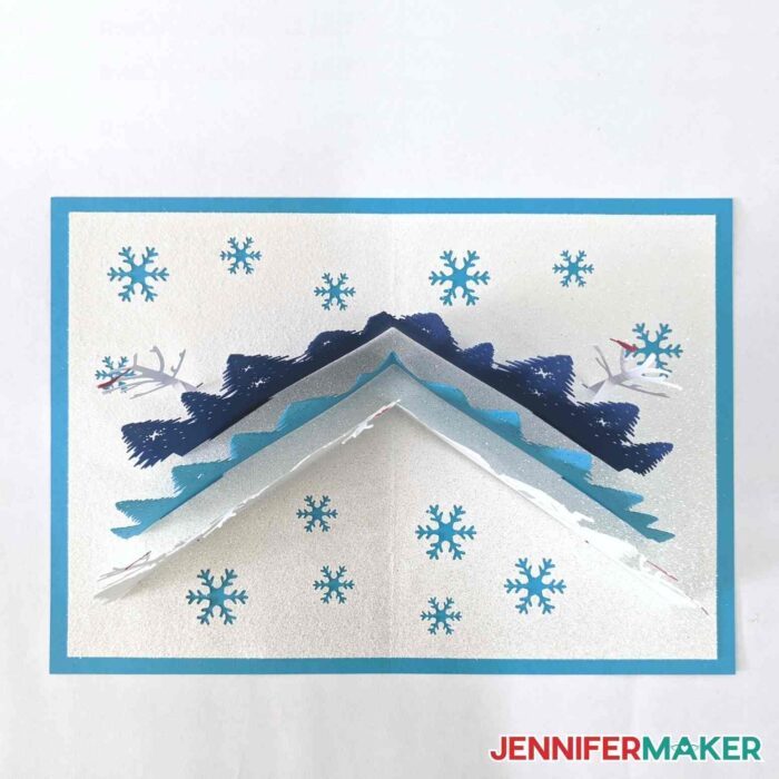 Top view of a DIY winter pop-up card with trees and snowflakes