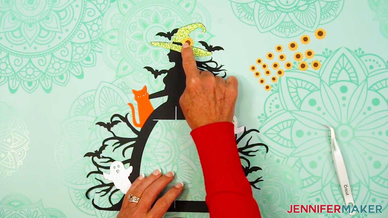 Take an extra-large sunflower and add a small dot of glue to its back, then adhere it to the witch&rsquo;s hat.