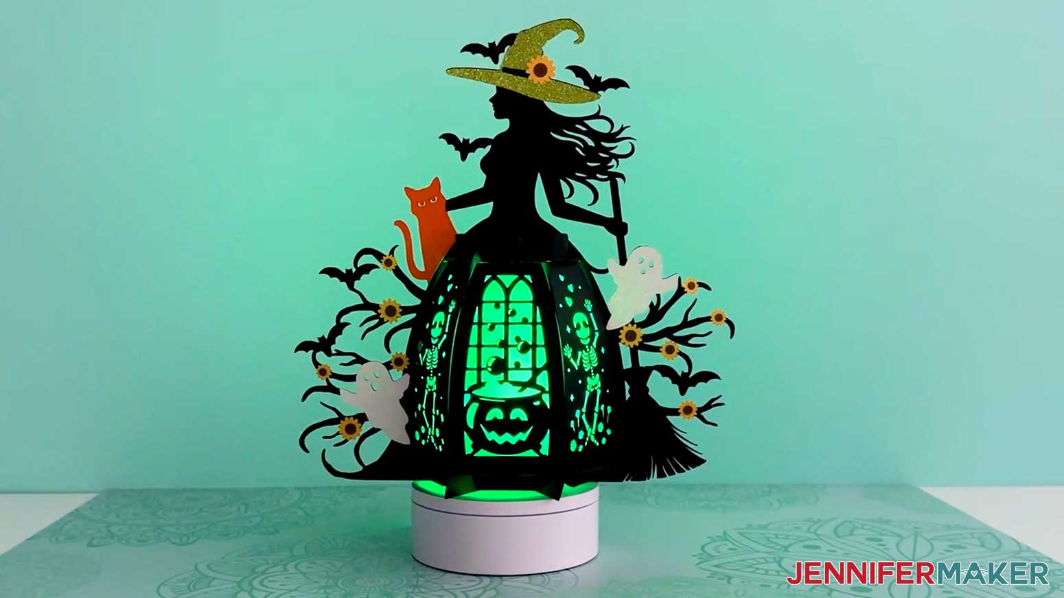 The finished witch lantern with colorful accessories and a green light inside the base.