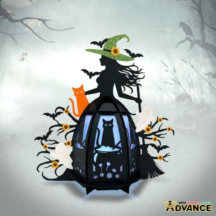 An enchanting Paper Witch Lantern lit up against a misty forest background, made of black cardstock with colored details and custom designed panels